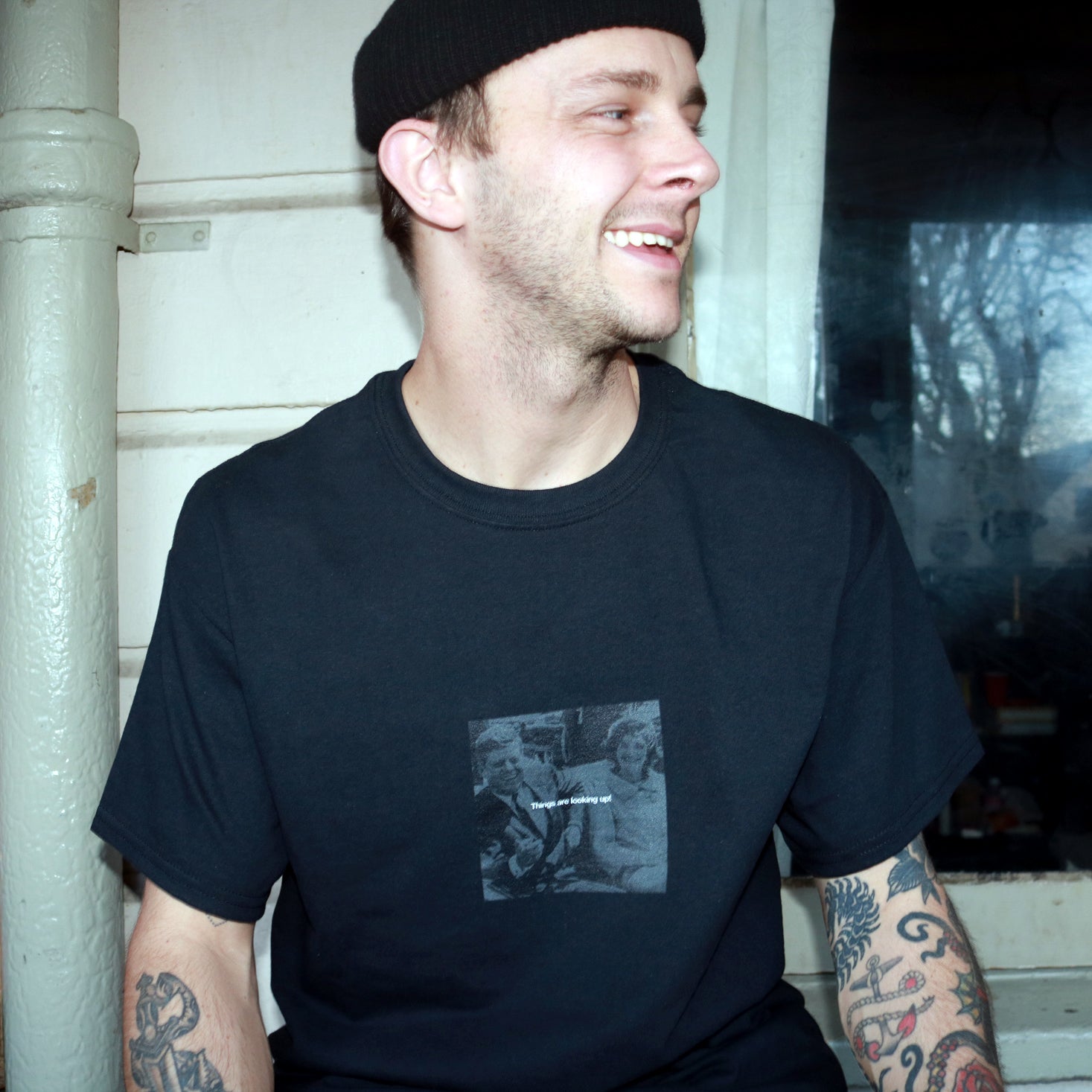 Dark humor streetwear design featuring White text of Things are looking up! over a black and white photo pre-assassination