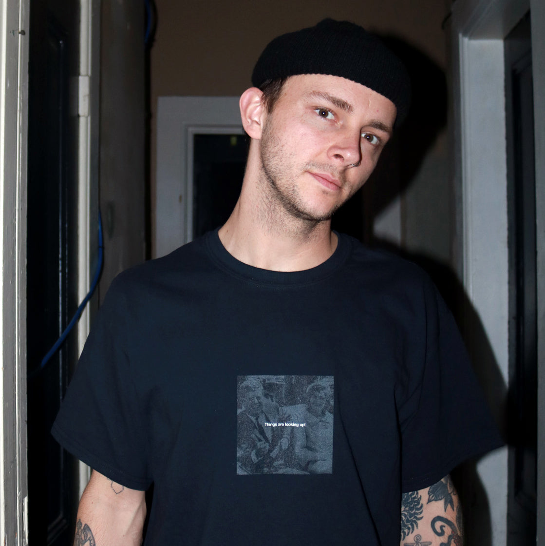 Dark humor streetwear design featuring White text of Things are looking up! over a black and white photo pre-assassination